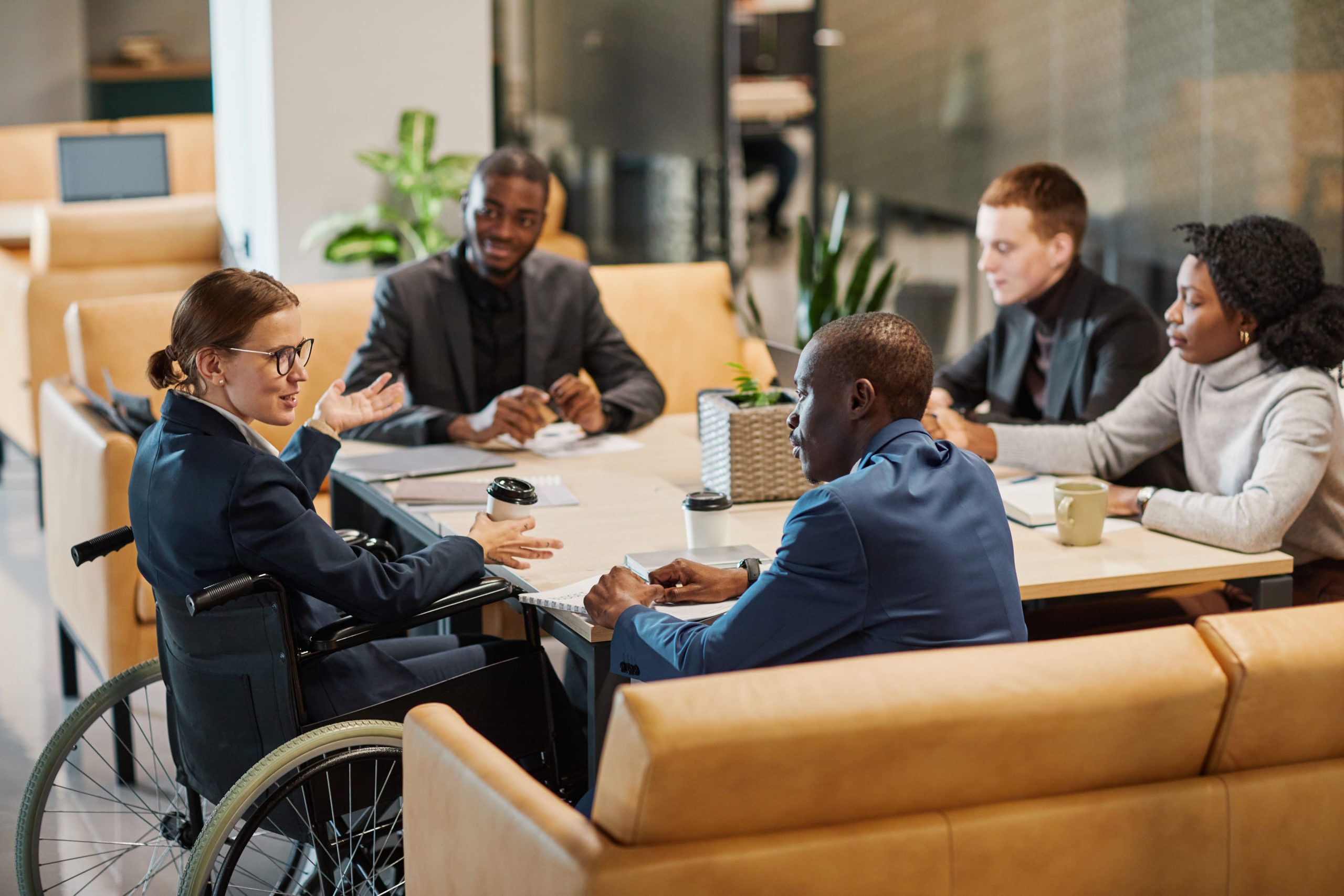 Businesswoman using wheelchair at meeting table at a business event.