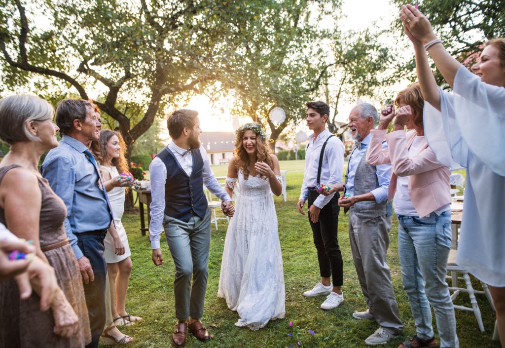 Bride, groom and guests at a small wedding reception outside in the backyard.