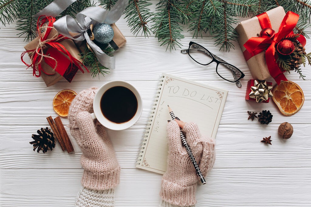 Woman drinking coffee and writing to do list on vintage notebook.