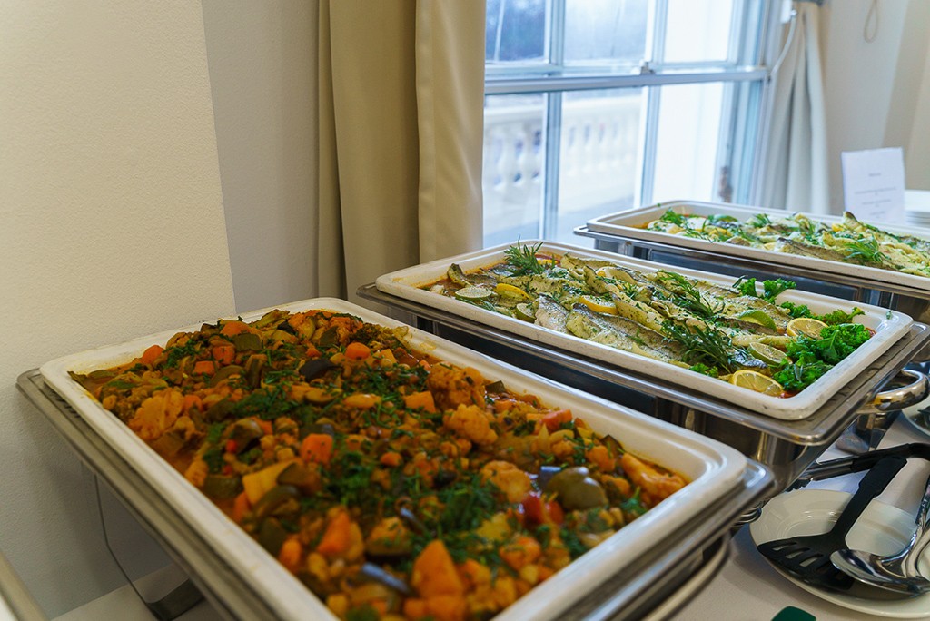 a buffet setup with roast veggies and fish options