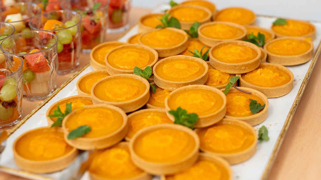 orange tartlets and mixed fruit cups in the background