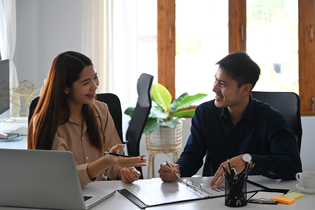 Two business partners discussing project strategy over a data report together.