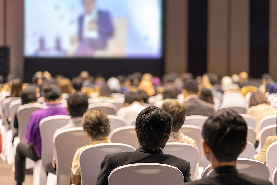 Rear view of Audience listening Speakers on the stage in the conference hall or seminar events